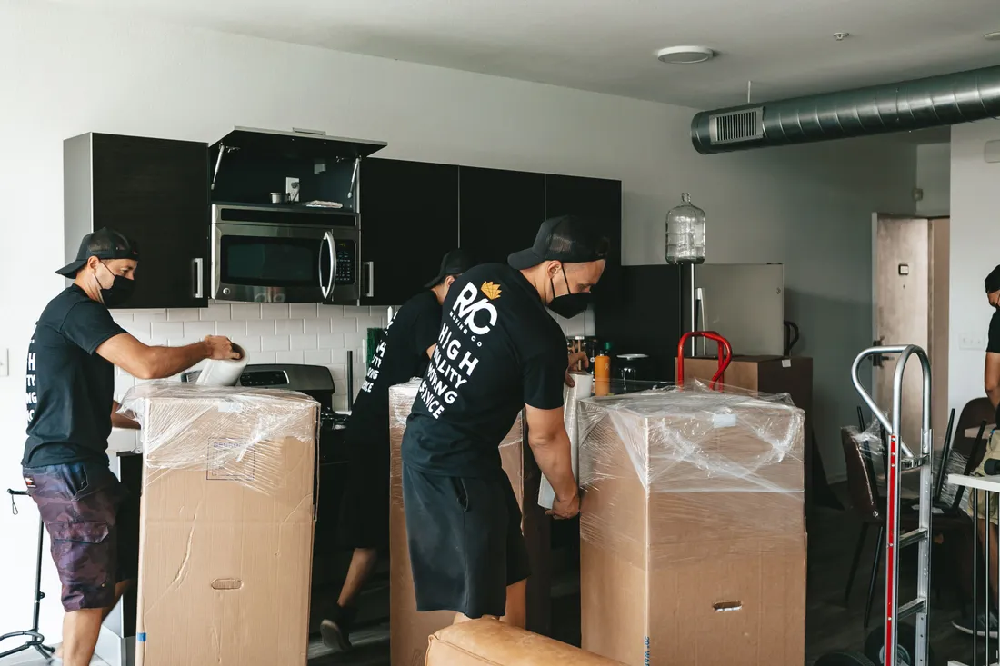 Team von BBE Umzüge & Transporte trägt ein verpacktes Möbelstück aus dem Haus